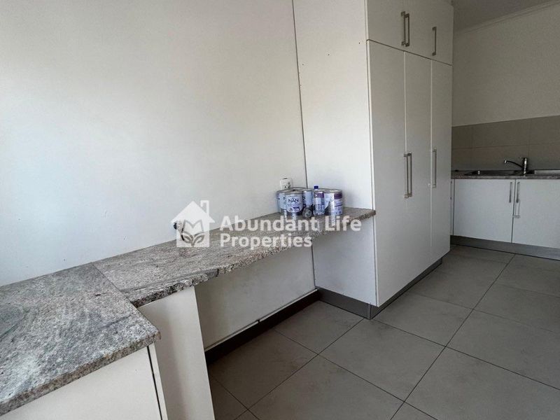 A clean, modern kitchen featuring granite countertops, ample built-in cabinetry, and neutral tiled flooring, offering a functional and well-maintained workspace.