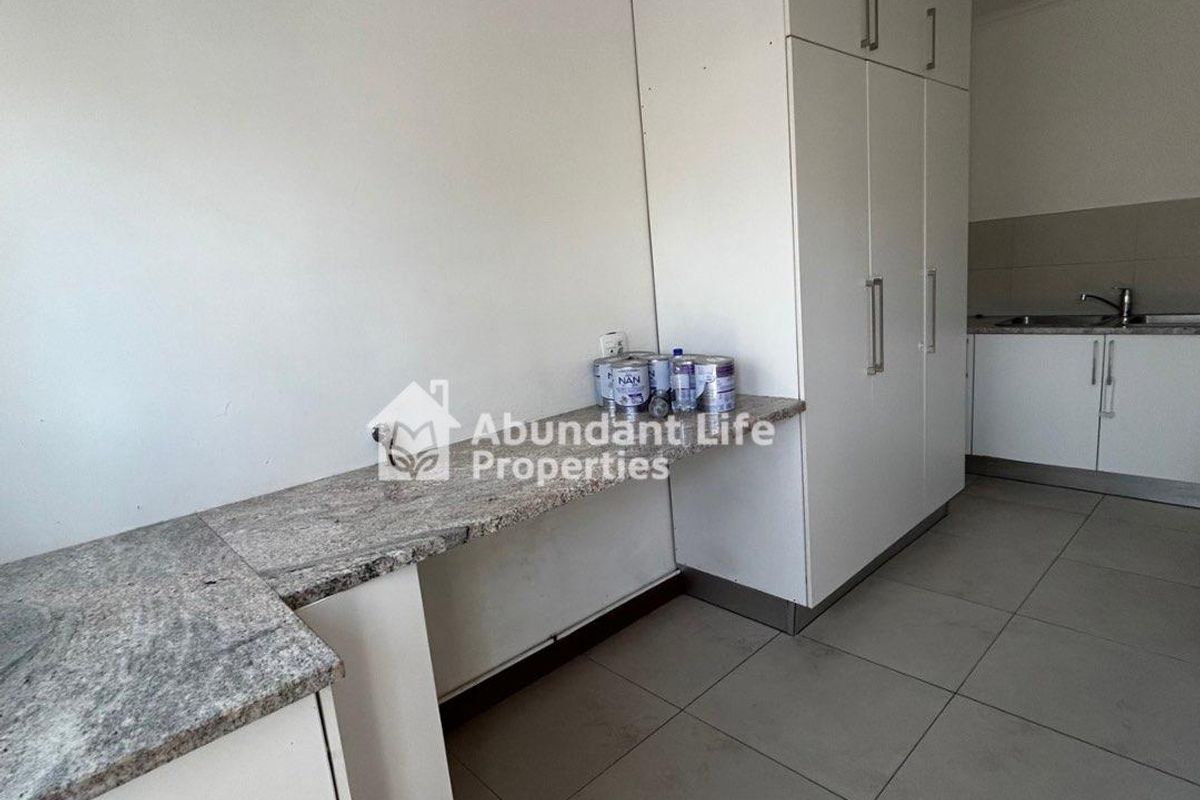 A clean, modern kitchen featuring granite countertops, ample built-in cabinetry, and neutral tiled flooring, offering a functional and well-maintained workspace.