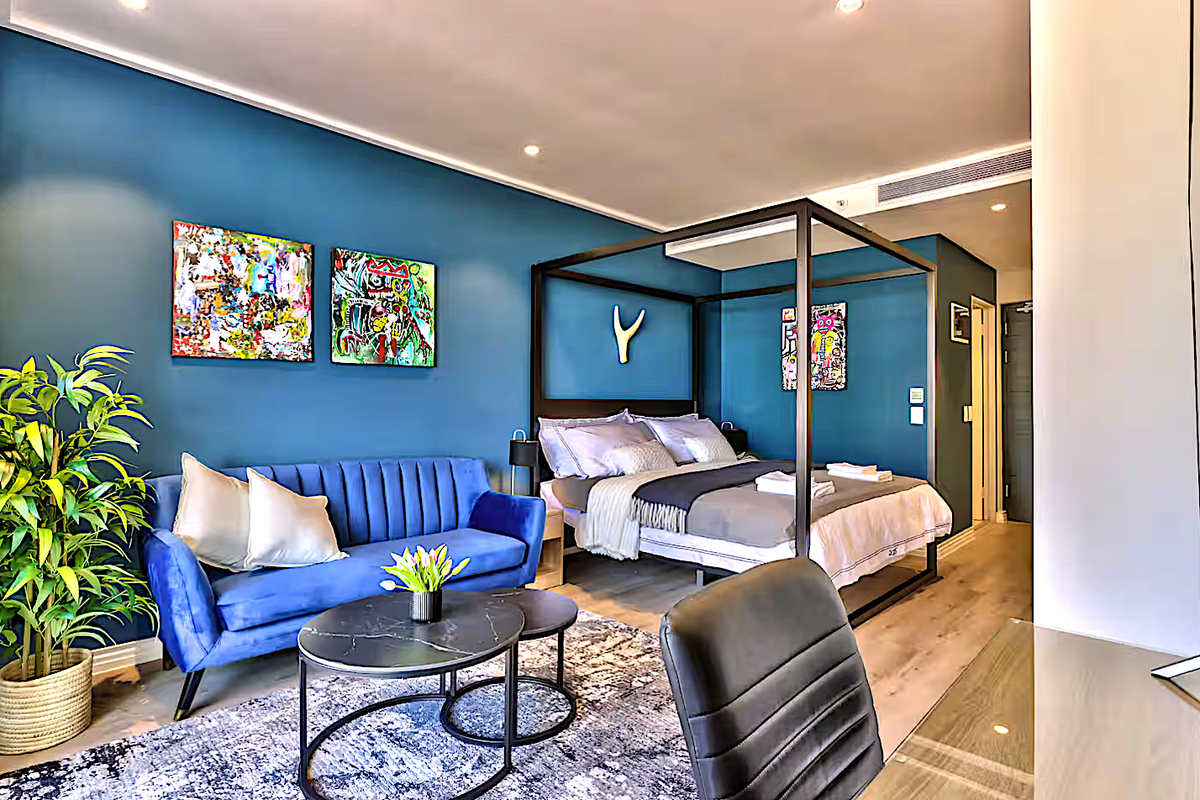 A modern, well-maintained bedroom featuring blue accent walls, recessed lighting, and integrated air conditioning, offering a comfortable and contemporary living space.