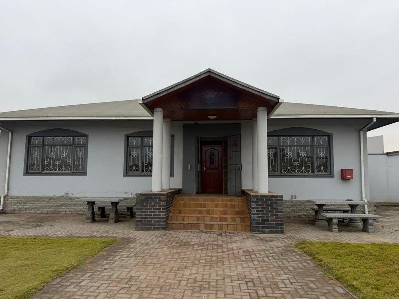 Front elevation of an office building featuring a covered entrance porch with concrete columns, brick steps, and security-enhanced windows.