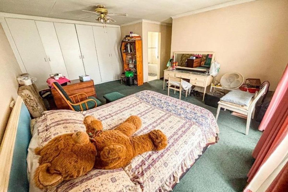 Spacious bedroom featuring extensive built-in wardrobe storage, ceiling fan, and direct access to an adjoining bathroom area.