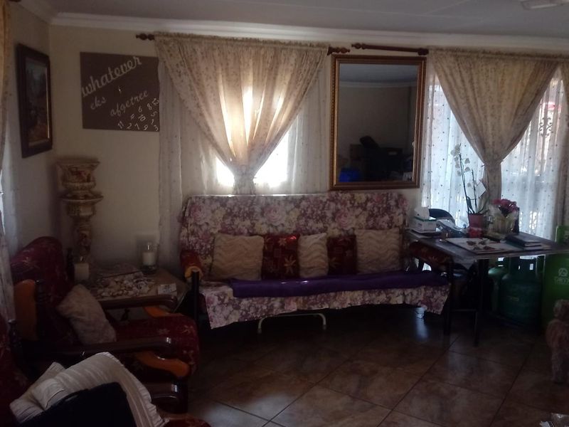 A living room area featuring tiled flooring and window treatments, providing a functional space for relaxation.