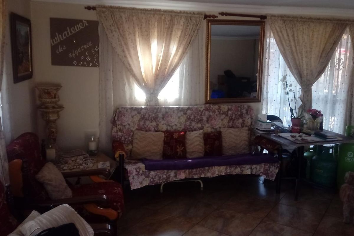 A living room area featuring tiled flooring and window treatments, providing a functional space for relaxation.