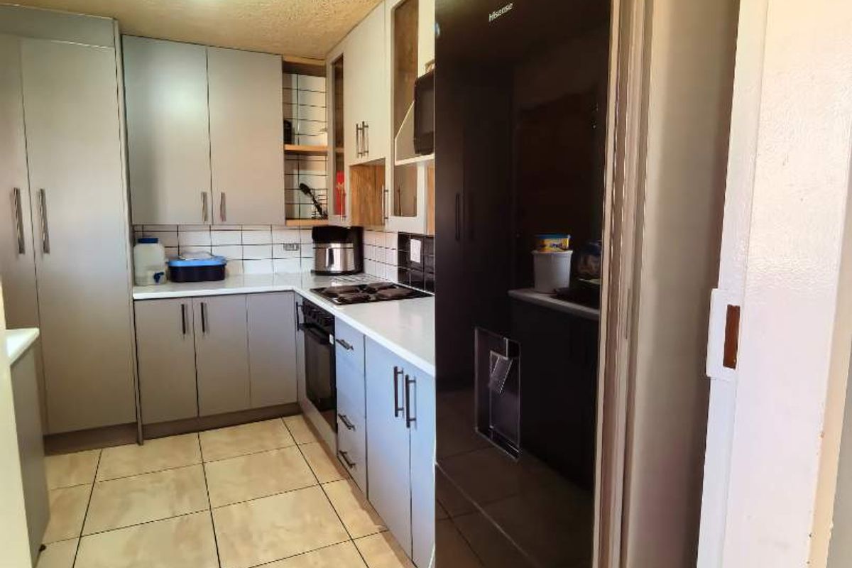 A functional kitchen featuring modern grey cabinetry, tiled flooring, a built-in oven, and a tiled backsplash.