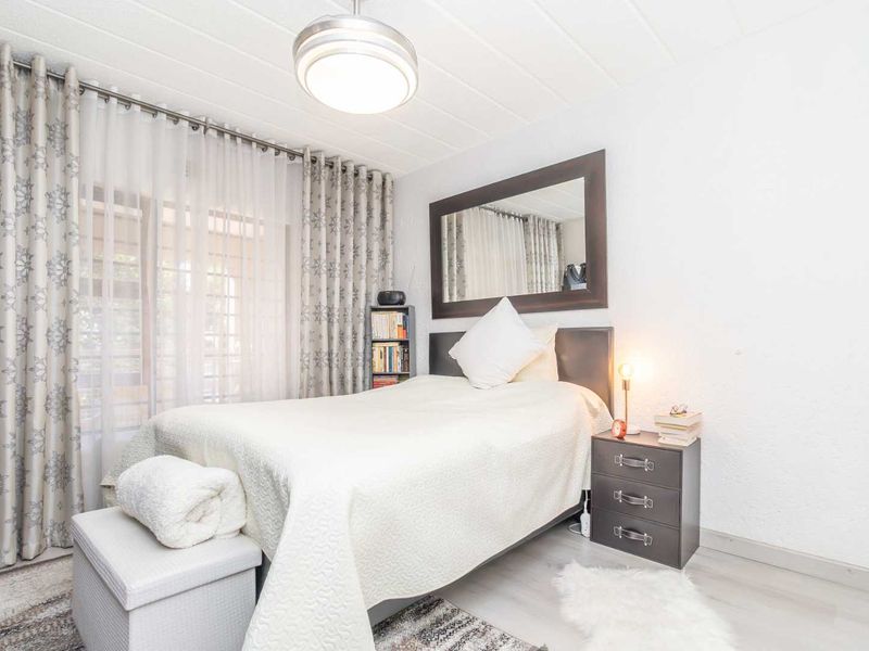 A well-lit bedroom featuring laminate flooring, a ceiling light fixture, and a sliding glass door providing access to the exterior.