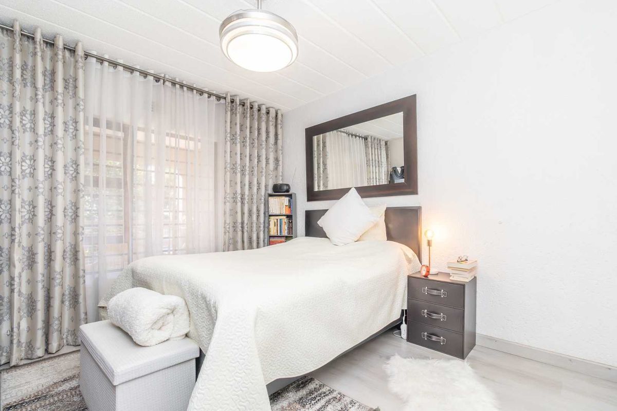 A well-lit bedroom featuring laminate flooring, a ceiling light fixture, and a sliding glass door providing access to the exterior.