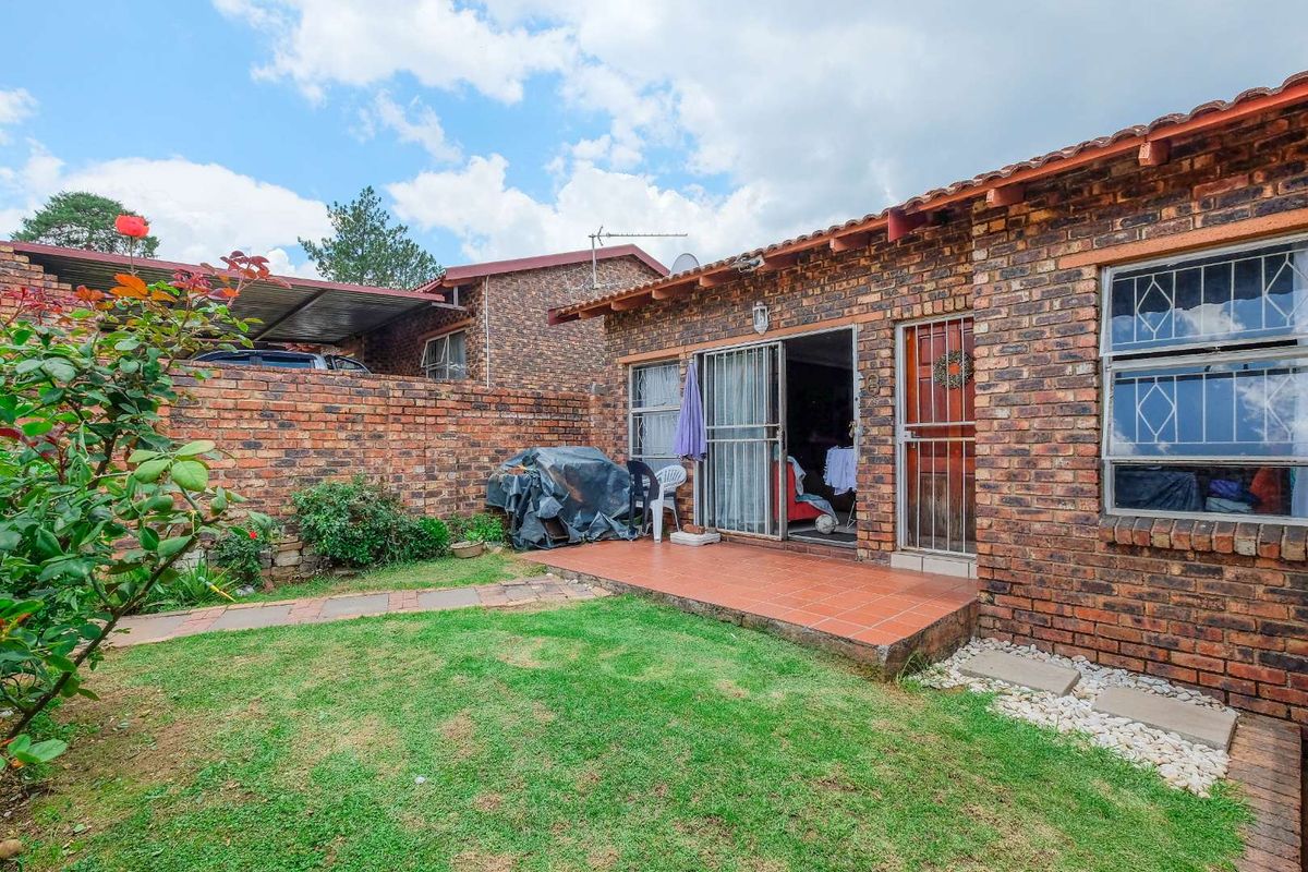 A private rear garden featuring a brick-paved patio area, established lawn, and direct access to the townhouse interior via sliding doors.
