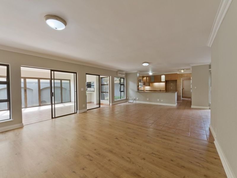 Spacious open-plan living and kitchen area featuring a mix of laminate and tile flooring, sliding doors to the patio, and functional built-in cabinetry.