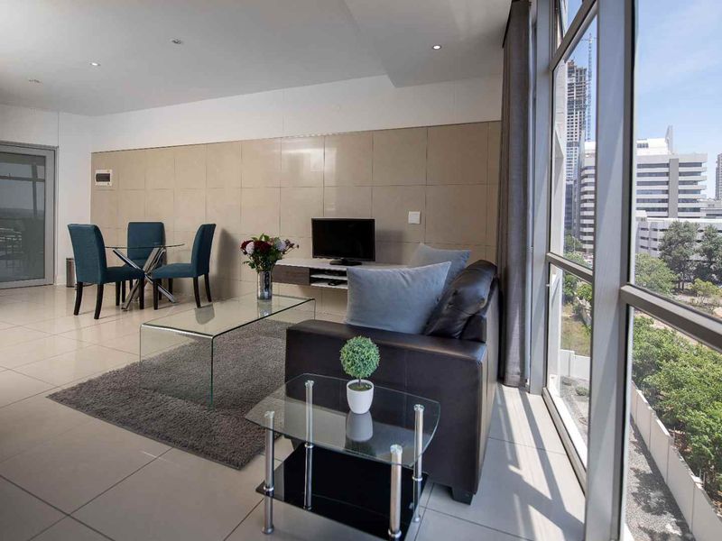 Modern open-plan living and dining area featuring large floor-to-ceiling windows with expansive city views and sleek tiled flooring.