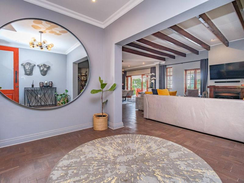 Spacious open-plan living area featuring elegant herringbone parquet flooring, exposed timber ceiling beams, and a cozy fireplace, creating a warm and inviting atmosphere.