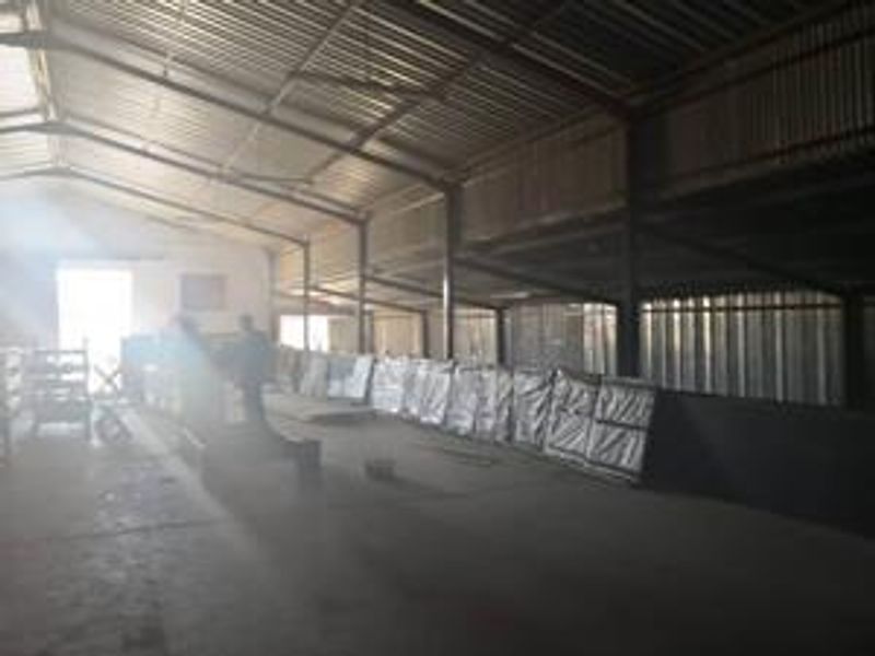 Spacious industrial utility area featuring a high-clearance corrugated metal roof, steel structural framing, and durable concrete flooring suitable for storage or manufacturing operations.