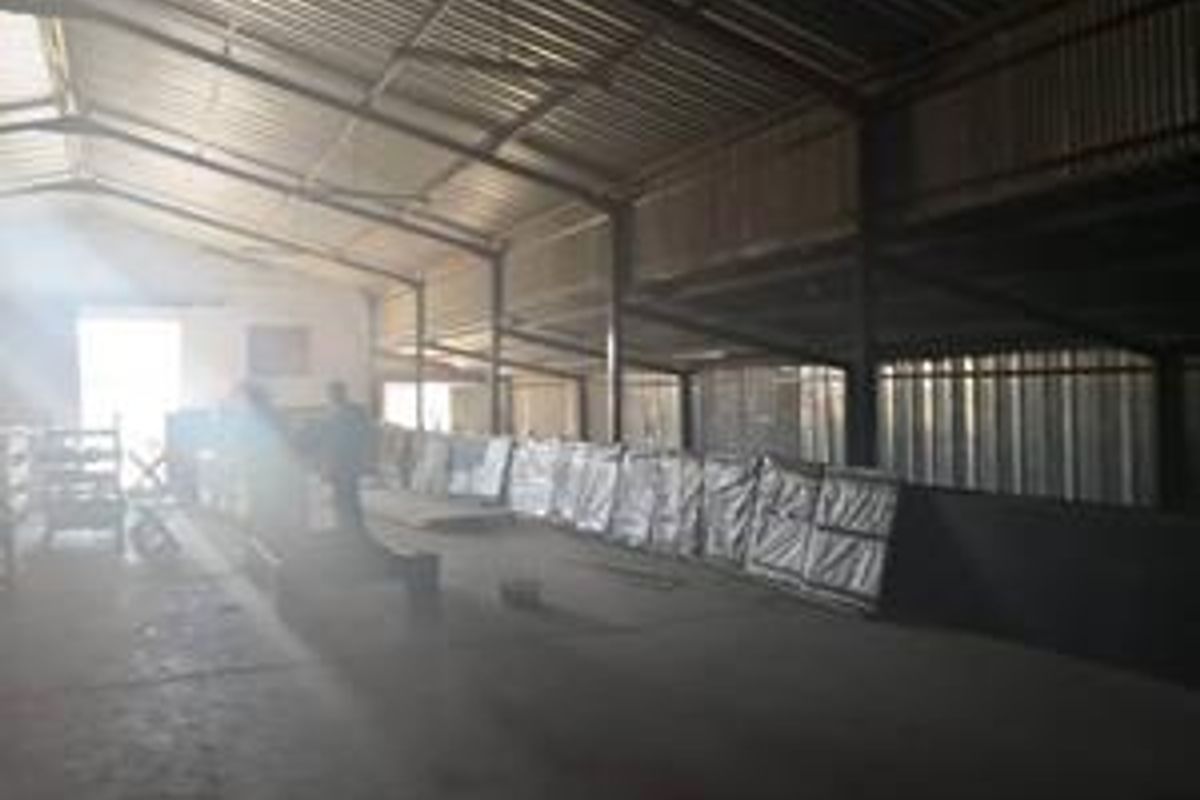 Spacious industrial utility area featuring a high-clearance corrugated metal roof, steel structural framing, and durable concrete flooring suitable for storage or manufacturing operations.