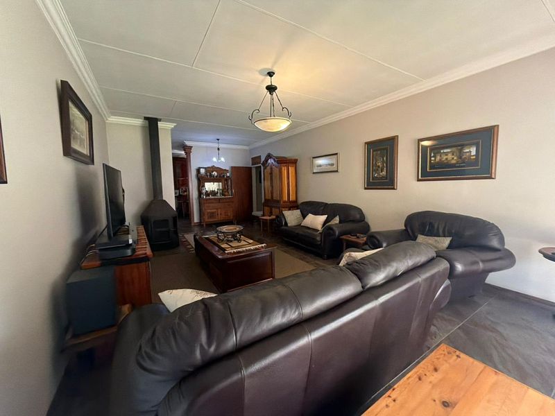 A comfortable living room featuring a freestanding fireplace, decorative ceiling cornices, and neutral wall finishes.
