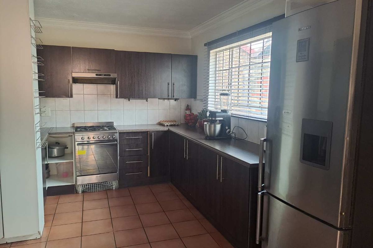 Functional kitchen featuring dark wood-look cabinetry, tiled splashback, stainless steel gas stove with extractor fan, and tiled flooring.