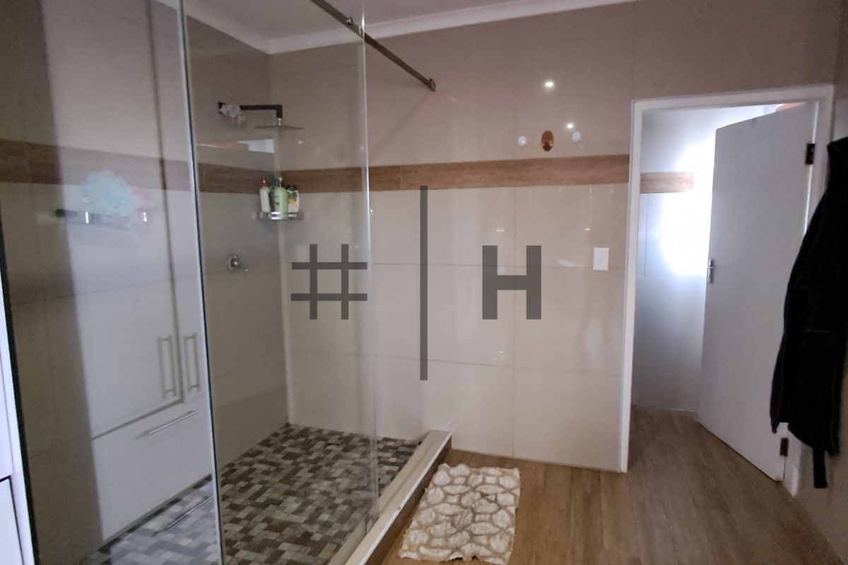 Modern bathroom featuring a glass-enclosed walk-in shower with mosaic tile flooring and neutral wall tiling.