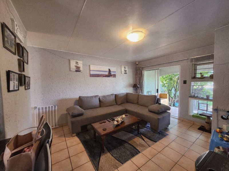 A comfortable living room featuring tiled flooring, textured walls, and a sliding glass door providing access to the outdoor area.