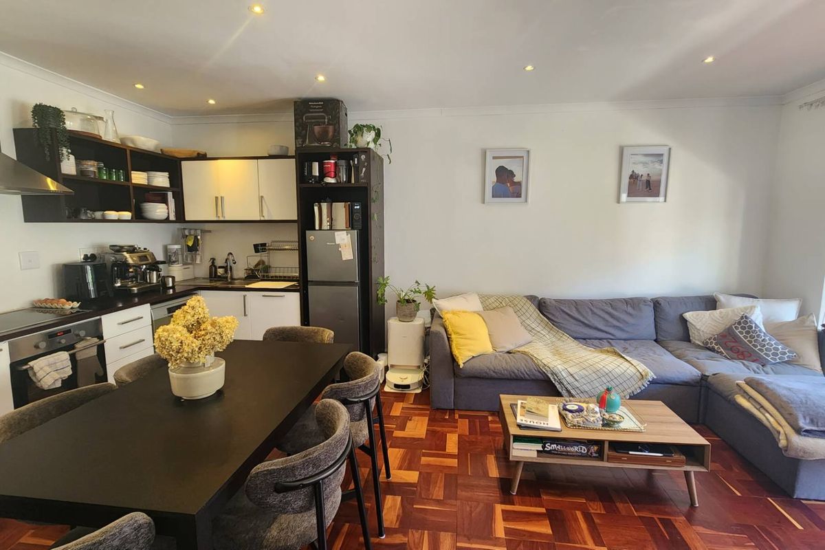 An open-plan living and kitchen area featuring classic parquet flooring, modern cabinetry, and integrated kitchen appliances, creating a functional and cohesive living space.