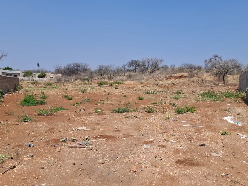 A vacant residential plot featuring boundary walls on both sides and existing electric fencing, ready for development.
