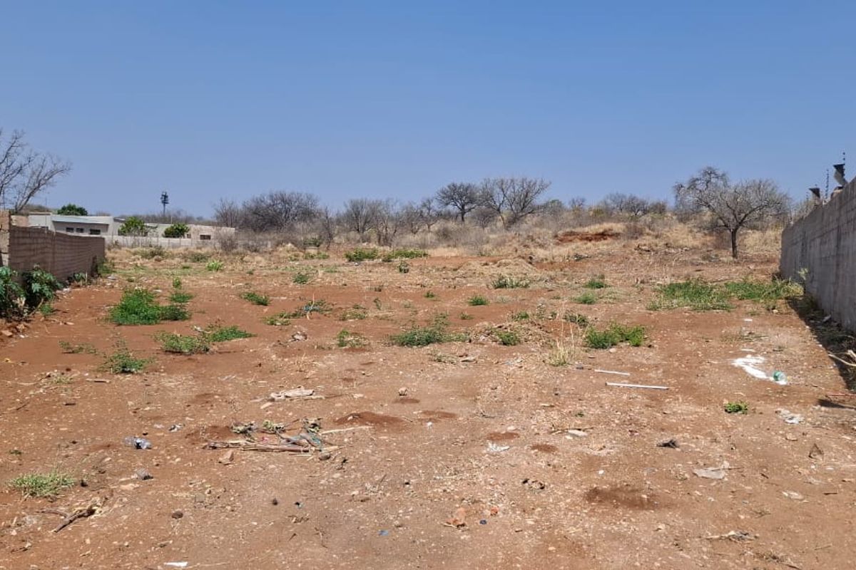 A vacant residential plot featuring boundary walls on both sides and existing electric fencing, ready for development.