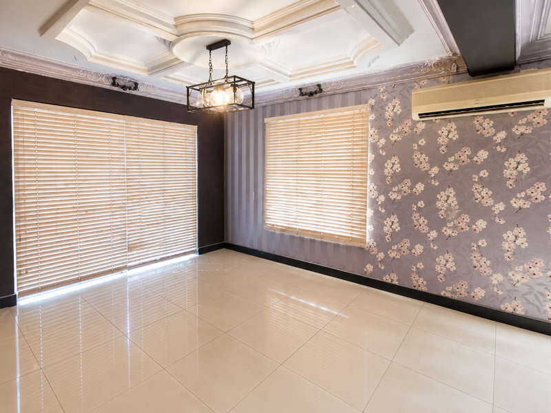 Spacious living area featuring elegant coffered ceilings, decorative floral wallpaper, polished tile flooring, and a wall-mounted air conditioning unit.