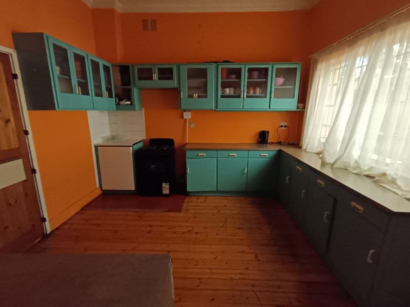 A dated kitchen featuring teal cabinetry, timber flooring, and a freestanding stove, offering significant potential for a modern renovation.