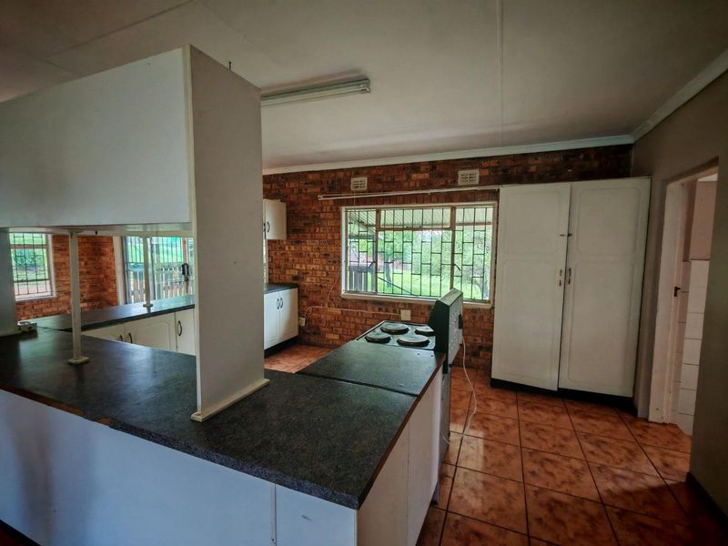 A dated kitchen featuring exposed brick walls, ceramic tile flooring, and built-in cabinetry with laminate countertops, offering significant potential for a modern renovation.