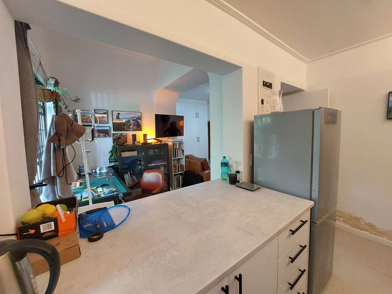 Open plan kitchen area featuring modern cabinetry and countertops, with visible wall damage near the floor requiring maintenance.