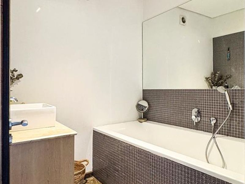 Modern bathroom featuring a built-in bathtub with mosaic tiling, a floating vanity with a vessel sink, and a large wall-mounted mirror.