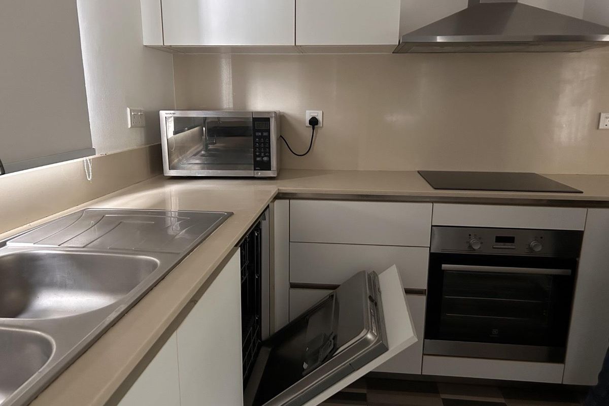 Modern kitchen featuring white cabinetry, integrated stainless steel oven, electric cooktop, extractor fan, and a double bowl sink with stone-look countertops.