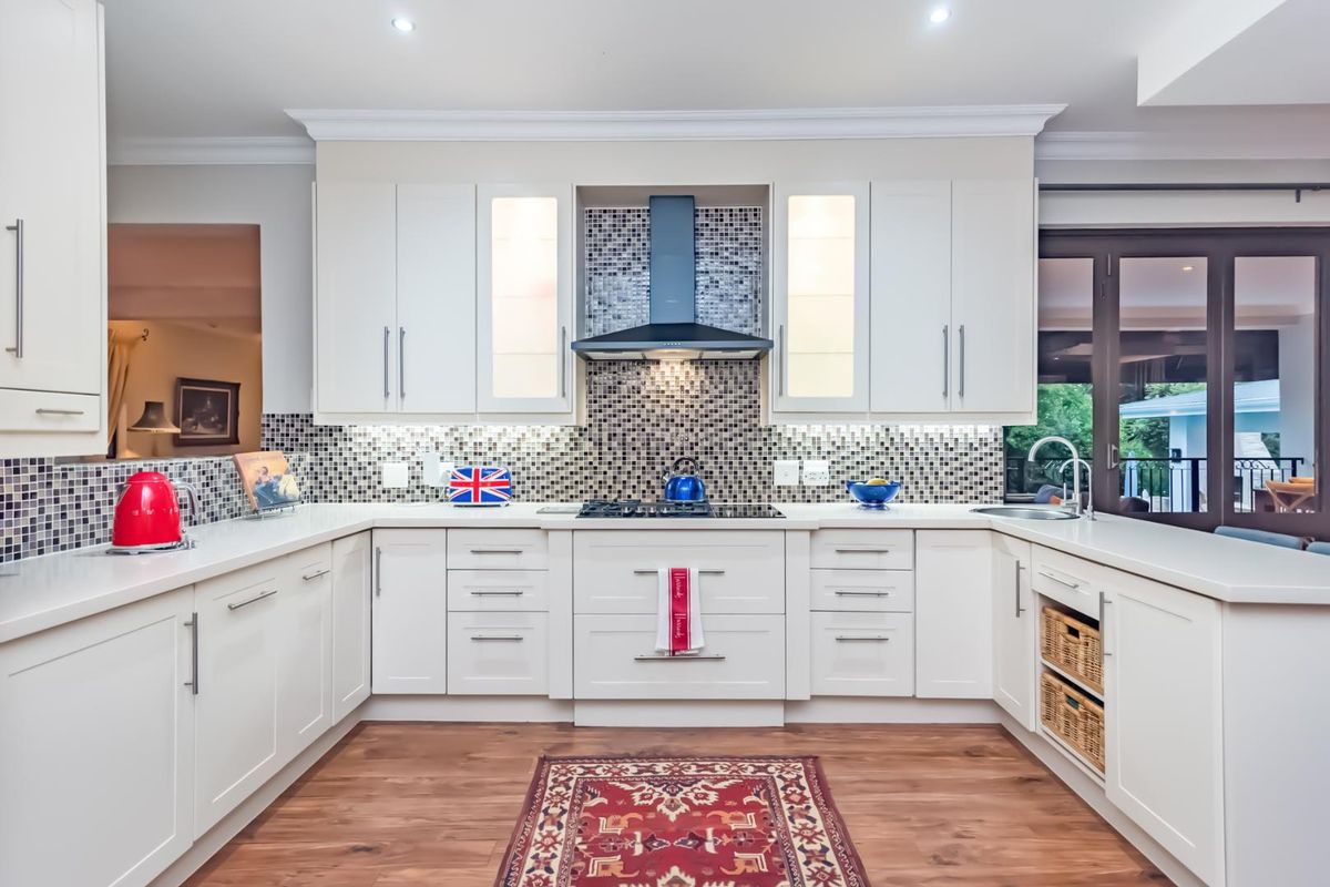 Modern kitchen featuring white cabinetry, mosaic tile backsplash, integrated gas hob with extractor fan, and high-quality finishes throughout.