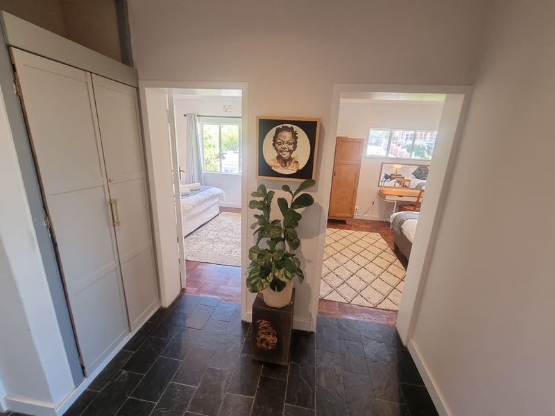 A bright hallway featuring dark slate flooring and built-in cabinetry, providing access to two separate bedrooms with parquet flooring.