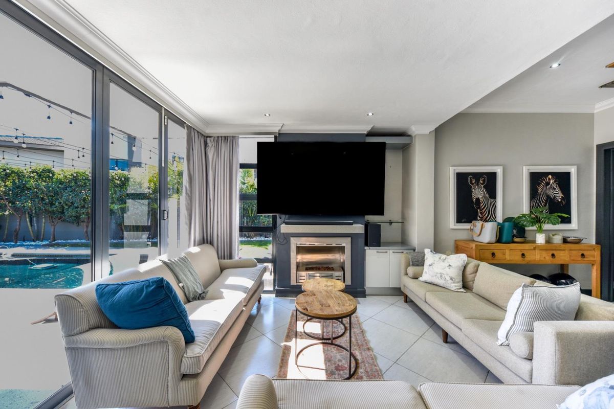 Spacious living room featuring a modern built-in fireplace, tiled flooring, and large sliding glass doors providing seamless access to the outdoor pool area.