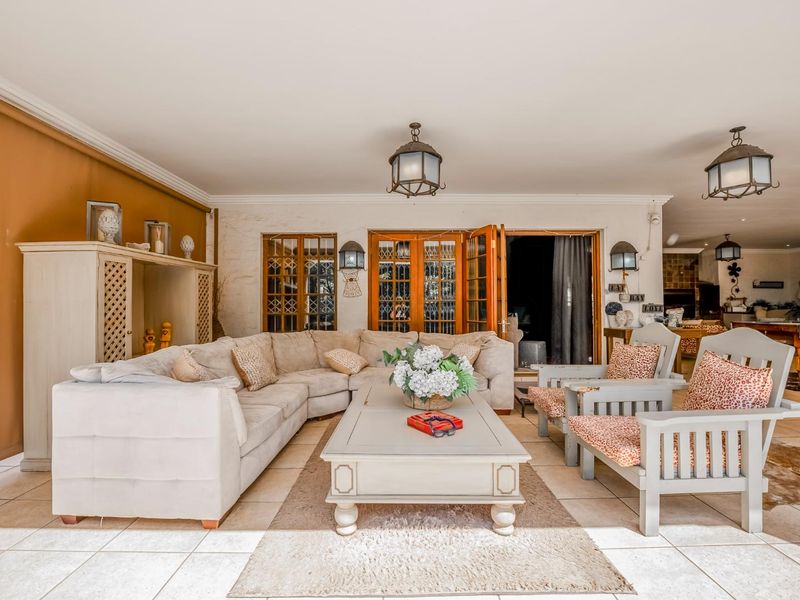A spacious covered patio area featuring tiled flooring, classic hanging lanterns, and direct access to the interior through wooden framed glass doors.