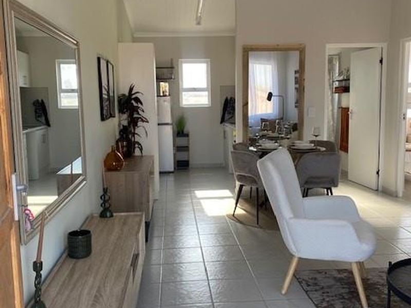 An open-plan living and dining area featuring tiled flooring, neutral wall tones, and direct access to the kitchen and adjacent rooms.