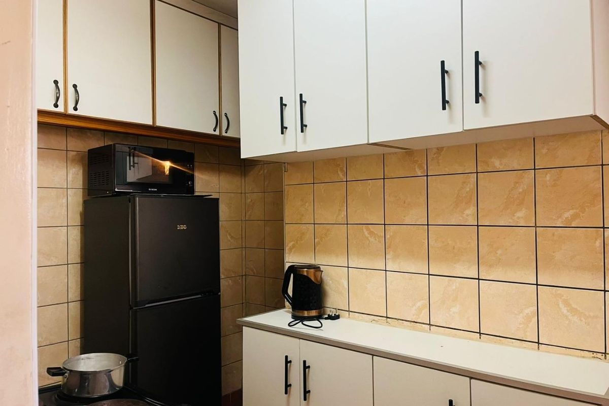 A functional kitchen featuring white cabinetry, tiled backsplash, and built-in cooking appliances, offering a practical layout for daily meal preparation.