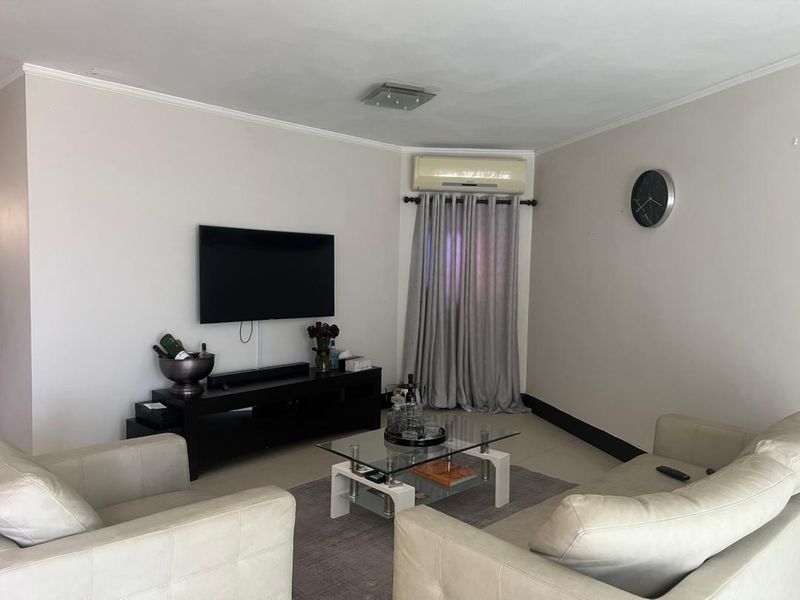A comfortable living room featuring tiled flooring, a wall-mounted air conditioning unit, and neutral wall finishes.