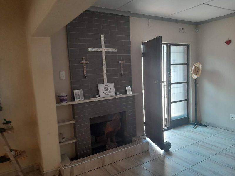 Living room featuring a grey brick fireplace, tiled flooring, and direct access to the exterior through a security gate.