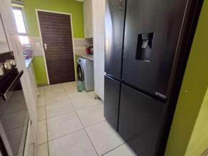 A functional scullery area featuring tiled flooring, built-in cabinetry, and an integrated oven, providing additional workspace and utility storage.
