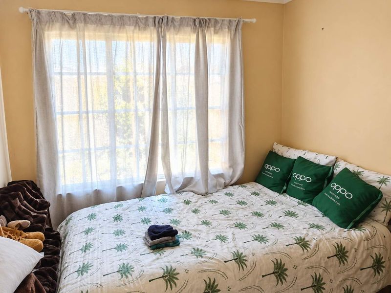 A simple bedroom featuring a window with natural light and neutral wall paint.