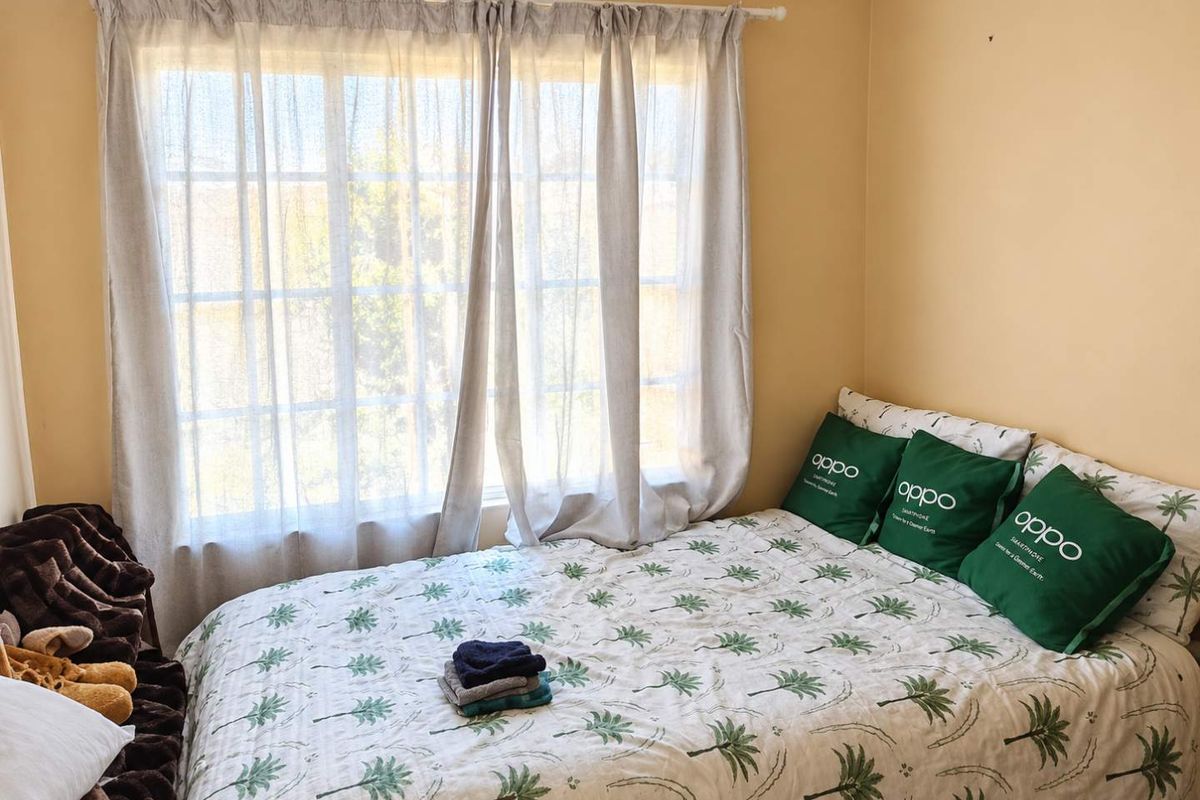 A simple bedroom featuring a window with natural light and neutral wall paint.