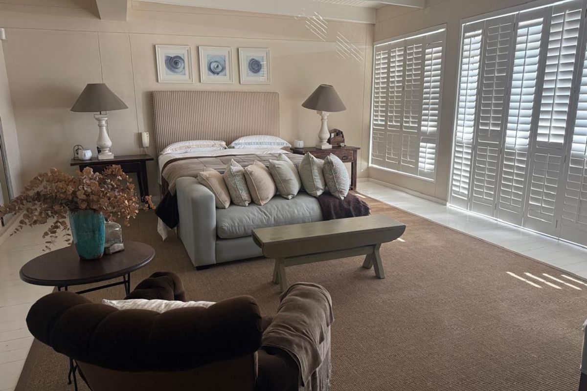 Spacious bedroom featuring plantation shutters, neutral wall finishes, and a high-quality ceiling design, offering a bright and comfortable living environment.