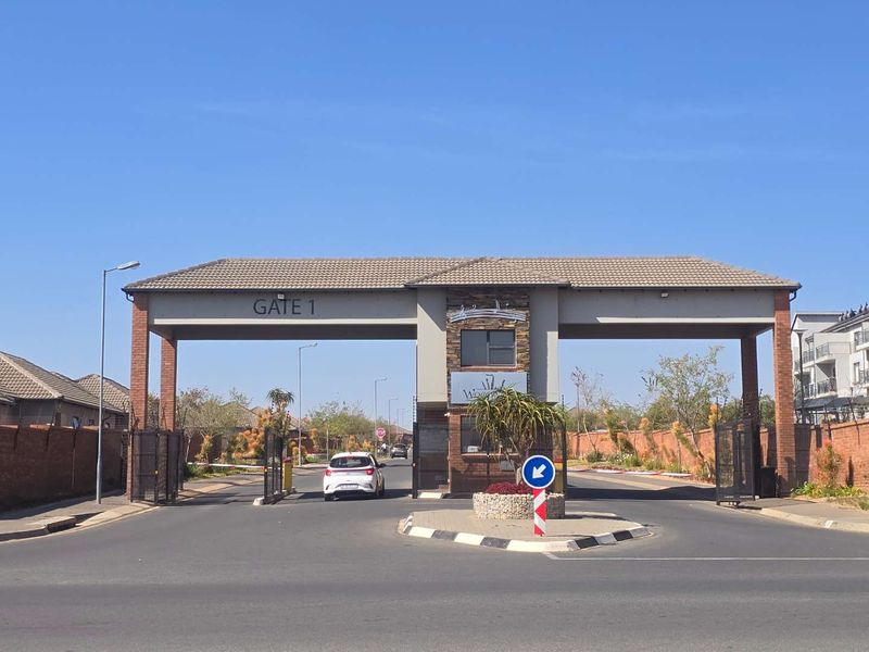 Main entrance gatehouse for the residential estate featuring brick pillars, stone cladding, and controlled access boom gates.