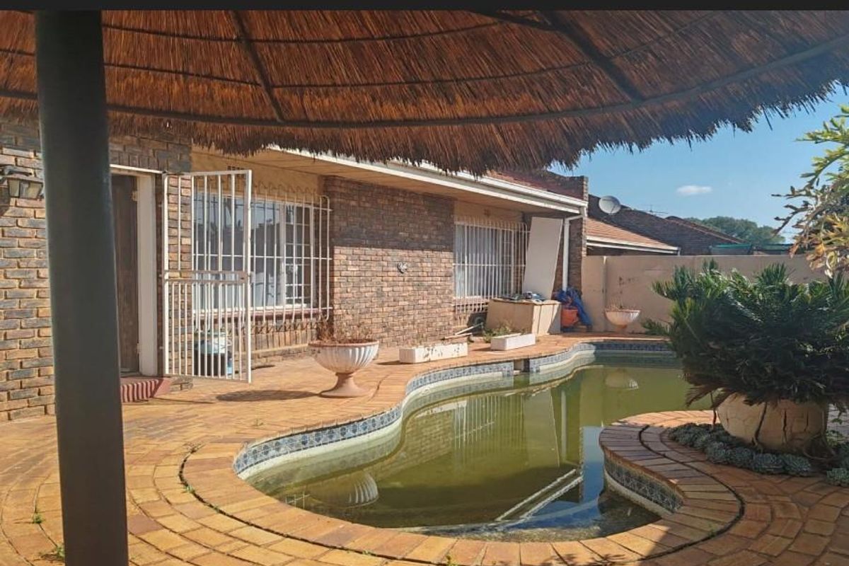 Outdoor pool area featuring a thatch lapa, brick paving, and a swimming pool requiring maintenance.