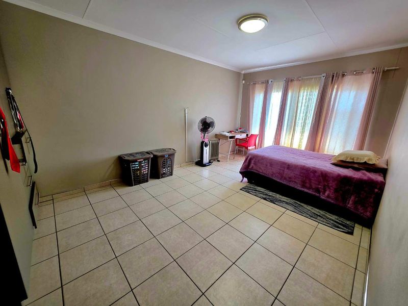 A spacious bedroom featuring neutral wall tones and durable tiled flooring, offering a versatile layout for various furniture arrangements.