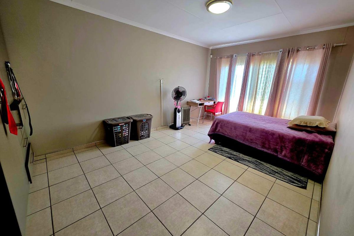 A spacious bedroom featuring neutral wall tones and durable tiled flooring, offering a versatile layout for various furniture arrangements.