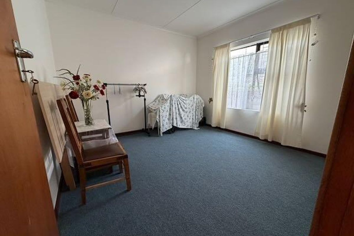 A bedroom featuring blue carpeting, a window with curtains, and a simple interior layout.