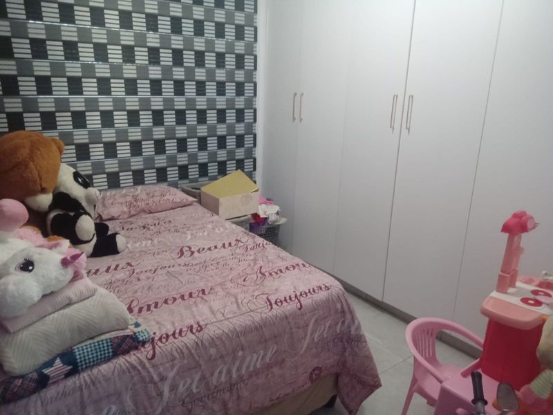 A bedroom featuring built-in cupboards and tiled flooring, offering a functional space with neutral finishes.