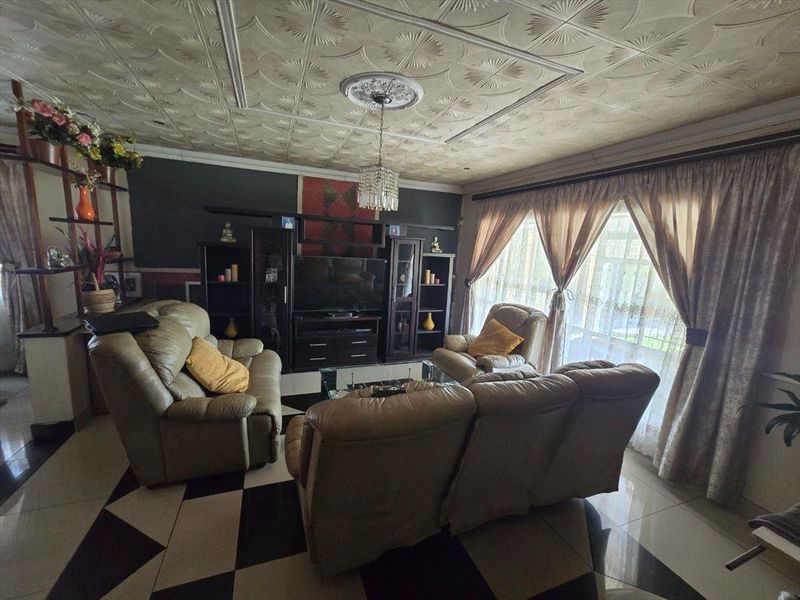 A living room featuring decorative ceiling tiles, a central ceiling rose, and tiled flooring, providing a distinct character to the space.