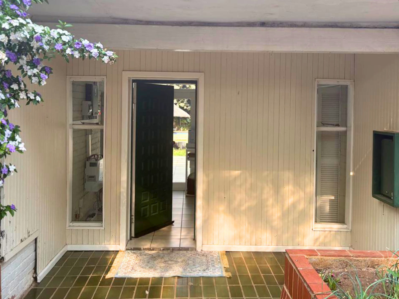 Covered entrance porch featuring vertical timber cladding, tiled flooring, and a brick planter box, providing a welcoming approach to the home.