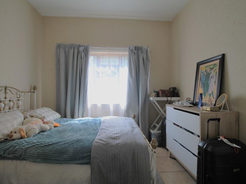 A functional bedroom featuring tiled flooring and a central window, providing a neutral base for personalization.